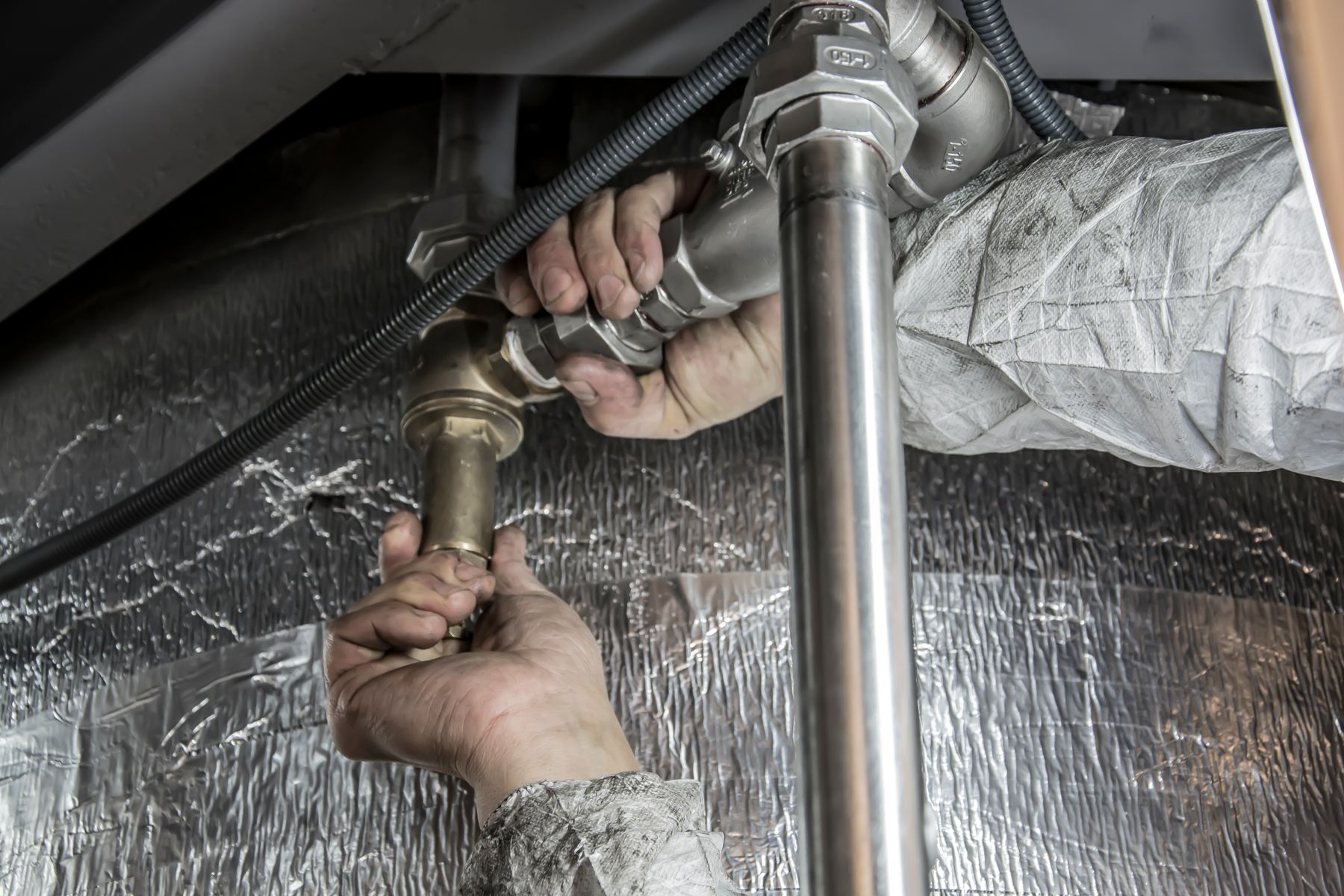Licensed plumber tightening a fitting on a residential job